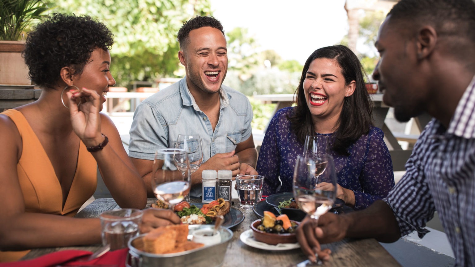 Four people are laughing while having dinner together