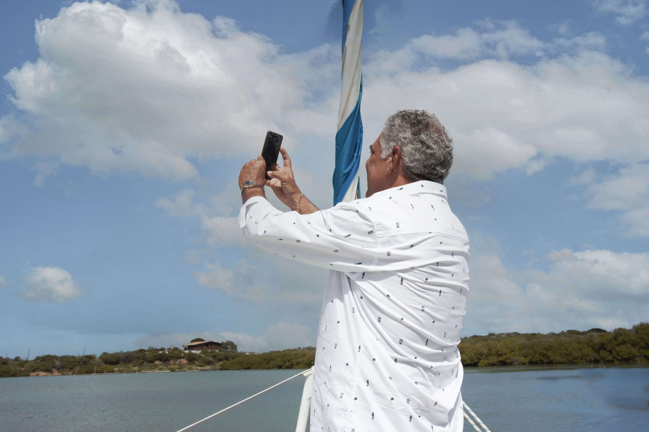 Man holds his phone in front of a boat